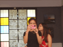 a woman taking a picture of herself with a pink phone