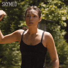a woman in a black tank top is holding a hammer in her hand .