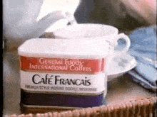 a can of cafe francais coffee is on a table next to two cups of coffee .