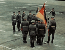 a group of men in military uniforms stand in a line with a flag that says ' germany ' on it