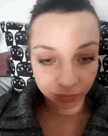 a close up of a woman 's face with a cat patterned pillow in the background
