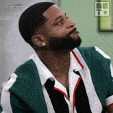 a man with a beard is wearing a green and white striped shirt and earrings
