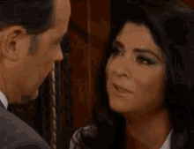 a man in a suit and tie is kissing a woman in a dark room .