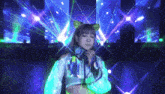 a woman wearing headphones and a cat ear headband is standing in front of a stage .