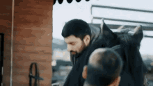 a man with a beard is standing next to a horse in a stable .
