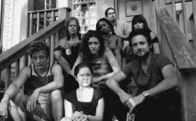 a black and white photo of a group of people sitting on the steps of a building .