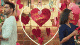 a man and a woman are standing in front of a valentine 's day decoration
