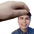 a hand is putting something on the forehead of a smiling young man .