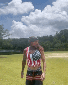 a man in an american flag crop top is standing in a grassy field