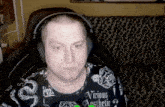 a man wearing headphones and a shirt that says vicious aesthetic is sitting on a couch