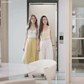 two women standing in front of an elevator with the words lingormoifss on the bottom