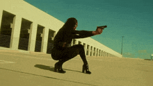 a woman is squatting down while holding a gun