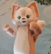 a stuffed animal in a fox costume is standing in front of a blue wall .