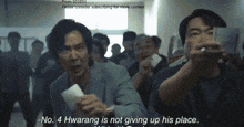 a group of people are standing in a room and one of them is saying " no 4 hwarang is not giving up his place "