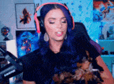 a woman with purple hair is wearing headphones and holding a small dog in front of a shure microphone