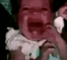 a baby is crying with its mouth open in a close up of its face .