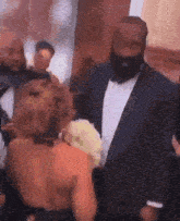 a man in a tuxedo is standing next to a woman in a dress at a party .