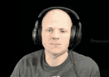 a bald man wearing headphones and a t-shirt with the letter t on the front