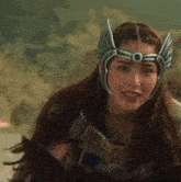 a woman wearing a helmet with wings is riding a horse and smiling .