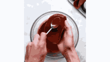 a person is holding a spoon over a bowl of chocolate sauce .