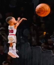 a young boy wearing a number 30 jersey is jumping in the air to throw a basketball