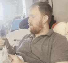 a man with a beard is sitting in a chair with his eyes closed and a newspaper in his hand .