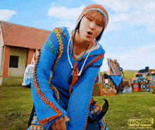 a person wearing a blue sweater and a beanie stands in a field