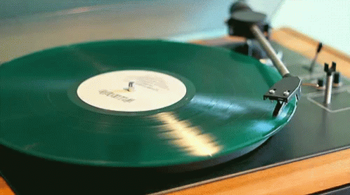A green vinyl record spinning on a record player's turn table.