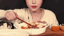 a woman is eating food with chopsticks and a spoon