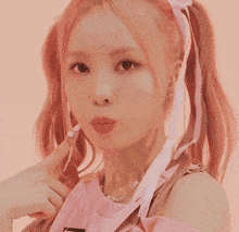 a woman with pink hair is wearing a pink top and pearls