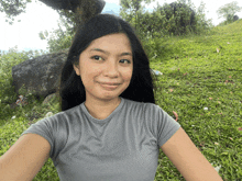 a woman in a grey shirt is taking a selfie