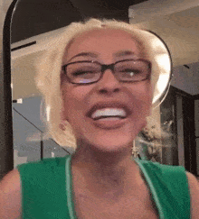 a woman wearing glasses and a green shirt is laughing .
