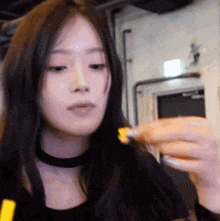 a woman with long black hair is eating french fries and looking at the camera .