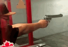 a man is holding a gun in front of a canadian maple leaf