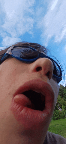 a close up of a person wearing sunglasses with their mouth wide open