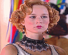 a woman wearing a black necklace and earrings looks at the camera