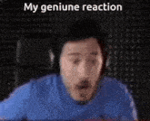 a man wearing headphones and a blue shirt is making a funny face in front of a black wall .