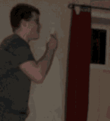 a man is standing in front of a red curtain holding a remote control .