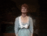 a woman in a blue dress is standing on a stage and singing .