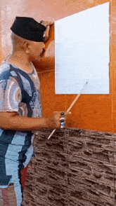 a man is holding a brush and painting a picture on a tiled wall .