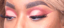 a close up of a woman 's eyes with pink eyeshadow