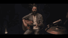 a man singing into a microphone with another man playing a keyboard behind him