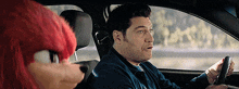 a man driving a car next to a stuffed animal
