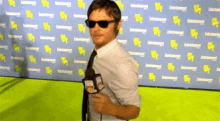 a man wearing sunglasses and a tie is holding a microphone