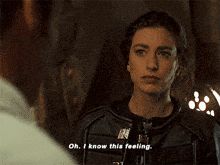 a woman in a leather jacket is talking to a man and says oh i know this feeling