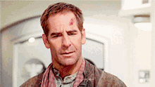 a man with a scarf around his neck and a scratch on his forehead