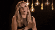 a woman in a black dress is smiling with her hands on her face .