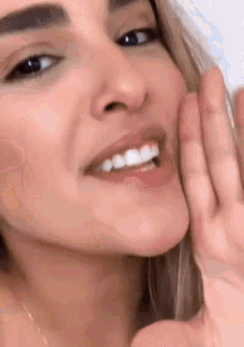 a close up of a woman 's face with her hand covering her mouth .