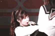 a girl singing into a microphone with another girl behind her