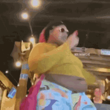 a man in a yellow shirt and colorful pants is dancing in a restaurant .